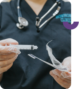 A healthcare worker taking a plastic syringe out of a package.