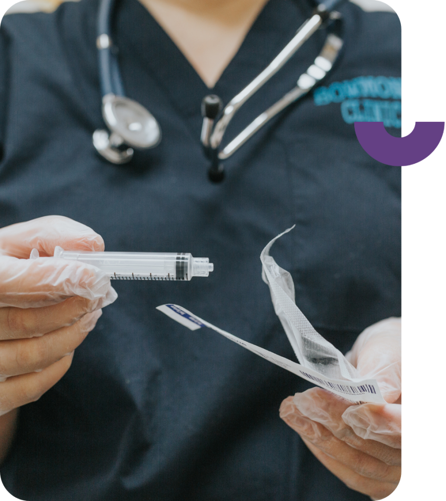 A healthcare worker taking a plastic syringe out of a package.