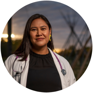 A woman with dark brown hair wearing a white lab coat with a stethoscope around her neck.